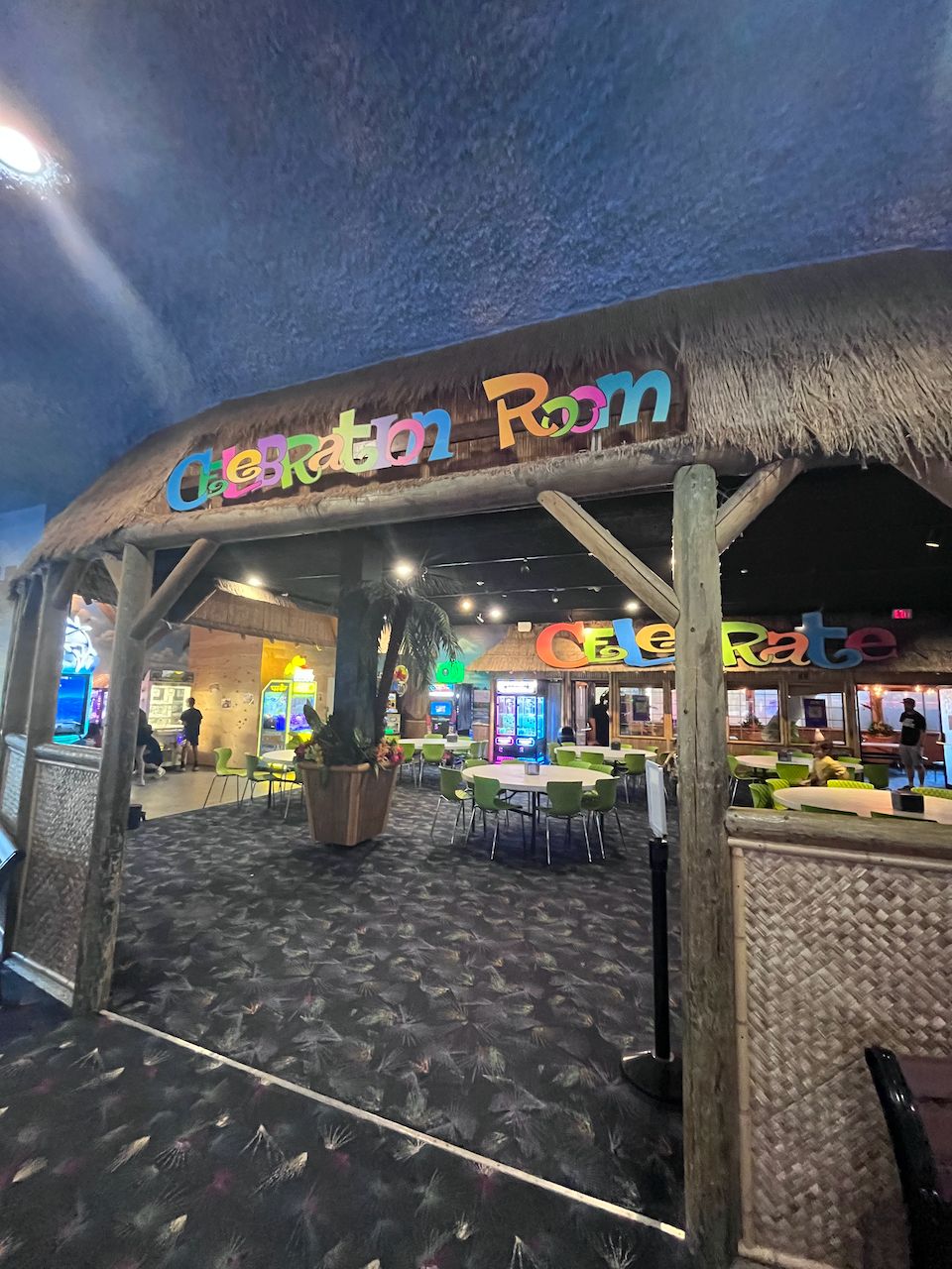 캐슬 펀 파크 셀러브레이션 룸 입구. 초가지붕 모양 구조물에 알록달록한 Celebration Room 간판이 붙어 있고 안쪽에 파티용 테이블이 놓여 있다